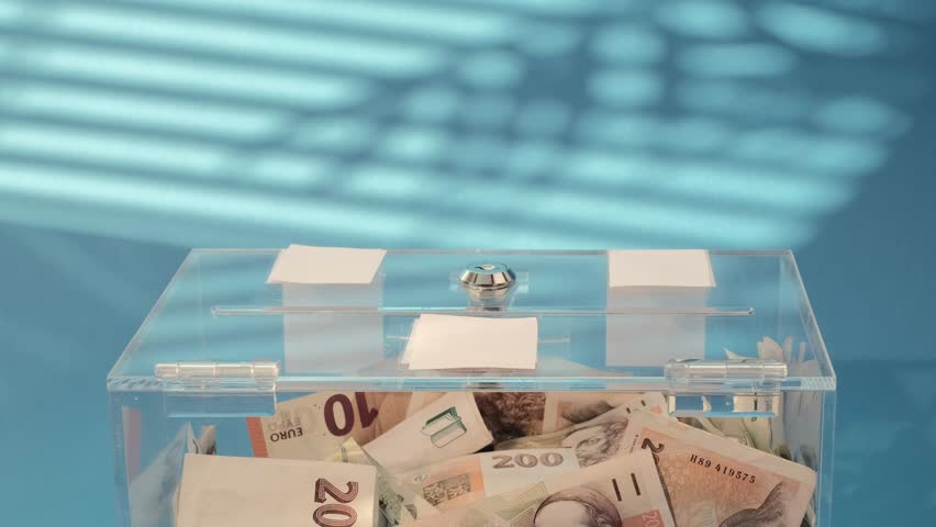 Hand put Charity and money CZK czech koruna banknotes into a transparent donation box for money donation. A financial support, collects money for a noble cause. The act of giving supports charitable i | Shutterstock HD Video #1111772239