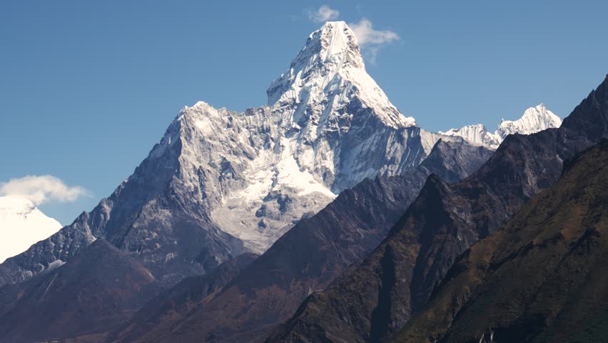 Snow covered Mount Ama Dablam rise above barren landscape of Himalayan Mountains. Trekking in Nepal to see highest mountains in world Royalty-Free Stock Footage #1111773229