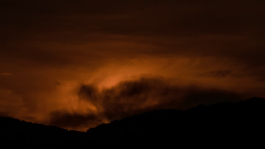 Time lapse of the sun rising over hills that are covered with clouds, in the style of smokey background.