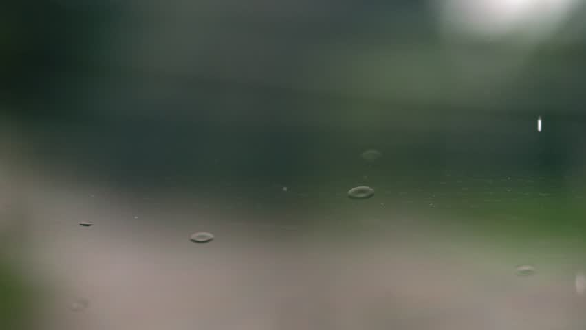 Raindrops streak down the glass in slow motion, with wipers battling the persistent autumn drizzle. | Shutterstock HD Video #1111776063