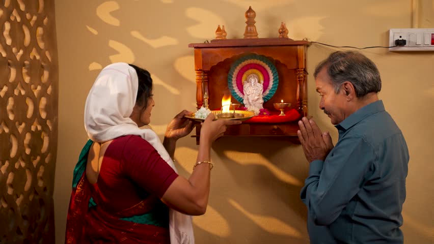 Devotional Indian woman giving aarthi to husband after offering to god at home - concept of spirituality, mindfulness and Hinduism. | Shutterstock HD Video #1111779493