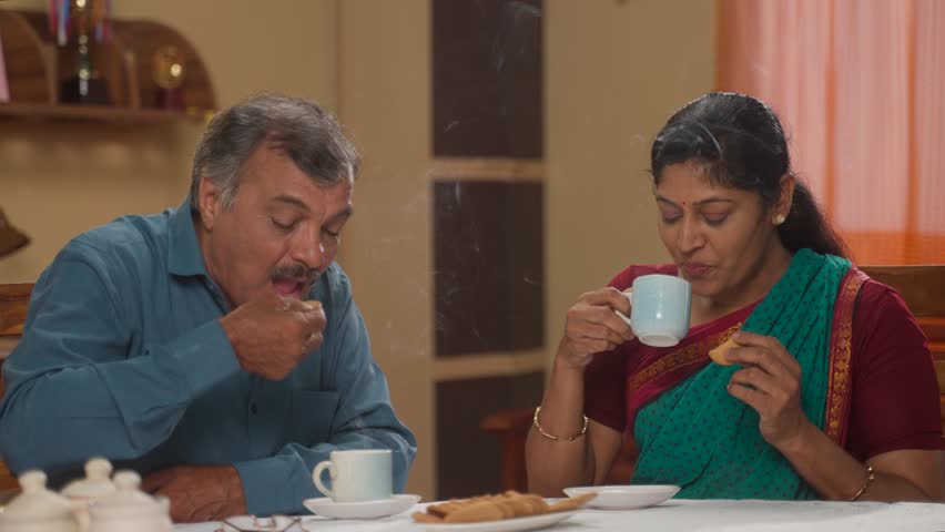 Indian senior couples enjoying morning tea and biscuits at home - concept of healthy morning routine, refreshment and retirement lifestyle | Shutterstock HD Video #1111779495