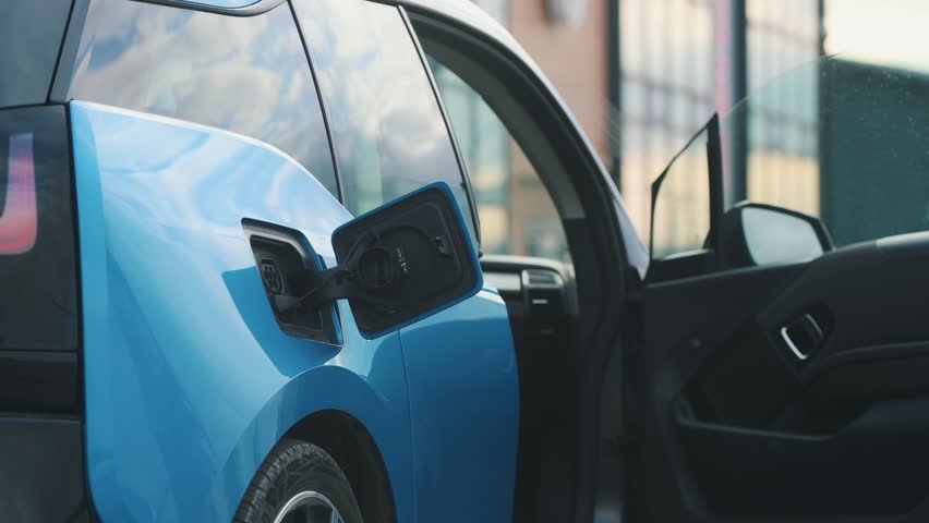 Beautiful woman connects plug to electric car in parking lot. Eco friendly alternative energy green environment concept. | Shutterstock HD Video #1111781929