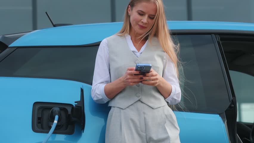 Beautiful woman connects plug to electric car in parking lot. Eco friendly alternative energy green environment concept. | Shutterstock HD Video #1111781981