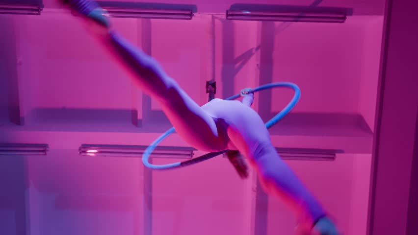 Athletic Beautiful Girl Aerialist Performs a Trick with a Split on an Aerial Ring. In Purple Neon Lighting, Slow Motion. Bottom angle. | Shutterstock HD Video #1111783837