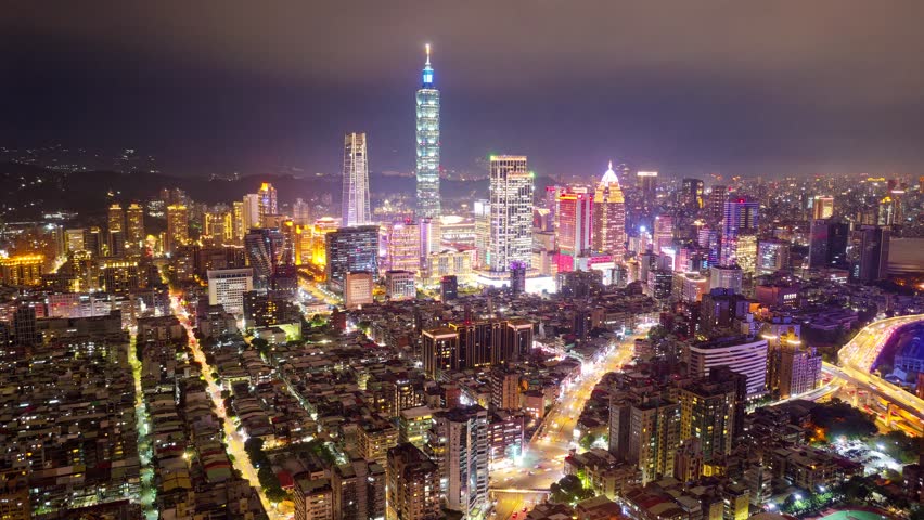 Aerial hyperlapse of Downtown Taipei, the vibrant capital of Taiwan, with famous 101 Tower standing out among modern skyscrapers in XinYi Commercial District and colorful city lights dazzling at night
