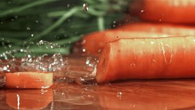 Knife cuts carrots with splashes. Filmed on a high-speed camera at 1000 fps. High quality FullHD footage