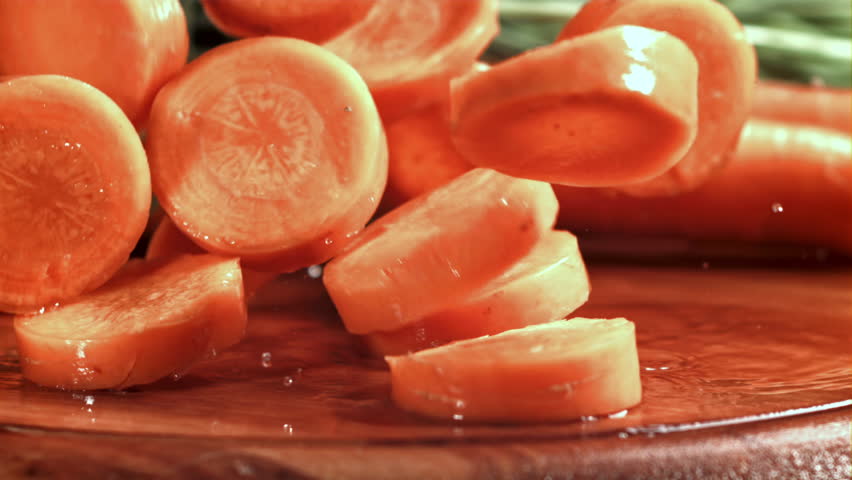 Pieces of chopped carrots fall onto a wet board. Filmed on a high-speed camera at 1000 fps. High quality FullHD footage