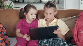 Two little sisters use digital tablet computer