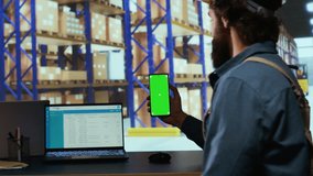 Delivery industrial advisor shows greenscreen display in warehouse storage room, working on cargo logistics for new order shipment. Depot supervisor holds isolated chromakey device. - Powered by Shutterstock - Get 15% off with code: PIKWIZARD15