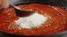 Adding grated cheese Parmesan to tomato sauce close-up. Cooking classic homemade Italian tomato sauce for pasta and pizza in the pan. Chef cooking traditional Italian food.  - Powered by Shutterstock - Get 15% off with code: PIKWIZARD15