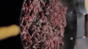 beef is stewed in a frying pan. Cook the beef in a frying pan. finely chopped beef meat, fried in a frying pan. Close-up of sliced raw beef meat in a frying pan. vertical orientation video