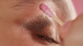 Closeup shot, style artist applies black mascara on the eyelashes of the female eye. Woman making make up using pink mascara. Professional makeup. Making mua. Smoky eyes - Powered by Shutterstock - Get 15% off with code: PIKWIZARD15