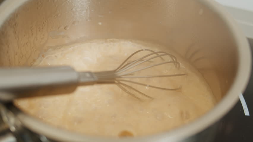 Chef is cooking sauce with whisk in a cafe restaurant kitchen. Creamy orange sauce close up | Shutterstock HD Video #1111793955