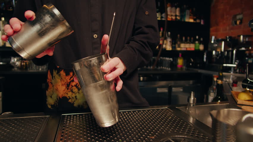 Young bartender doing a cocktail bloody mary with shaker in the bar. Man making red alcohol cocktail close up | Shutterstock HD Video #1111793959