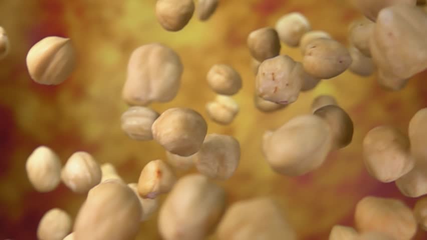 Close-up of peeled hazelnuts falling diagonally on a yellow ochre background in slow motion. High quality FullHD footage