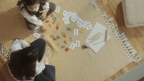 Mother and little daughter sitting on the floor at home and playing educational game with letters and word cards. Top down shot - Powered by Shutterstock - Get 15% off with code: PIKWIZARD15