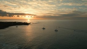 Aerial orbital clip of the sunrise with silhouetted boats yachts moored off the island of Lobos near Corralejo in Fuerteventura Canary Islands Spain
