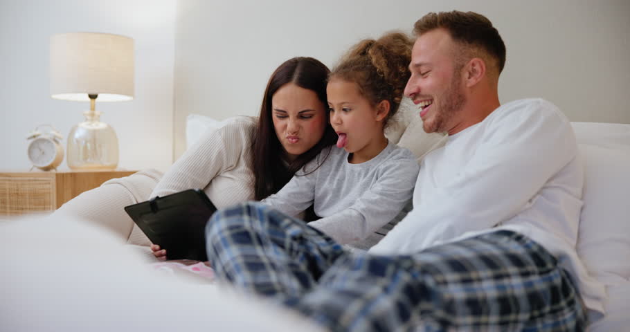 Happy, selfie and family with tablet on bed with funny, silly or goofy face expression at home. Smile, love and young girl child taking picture with parents on digital technology in bedroom at house. | Shutterstock HD Video #1111803587