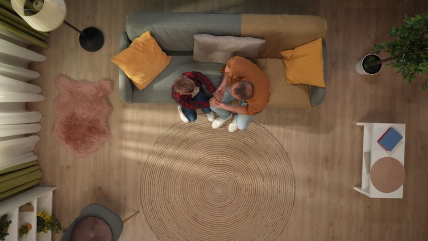 Top view of living room father and son sitting on the sofa, dad talking with kid holding hands and hugging. | Shutterstock HD Video #1111806075