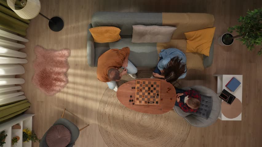 Top view of living room mom dad and son sitting playing chess together at the table, father winning match. | Shutterstock HD Video #1111806097