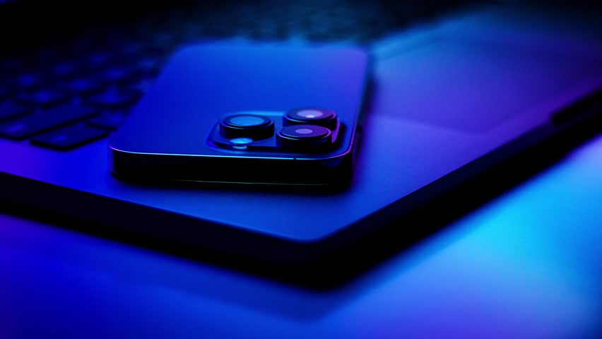 Close up of laptop and smartphone in neon light