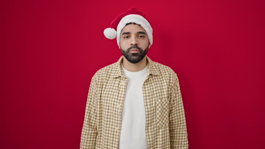 Young hispanic man wearing christmas hat having headache over isolated red background