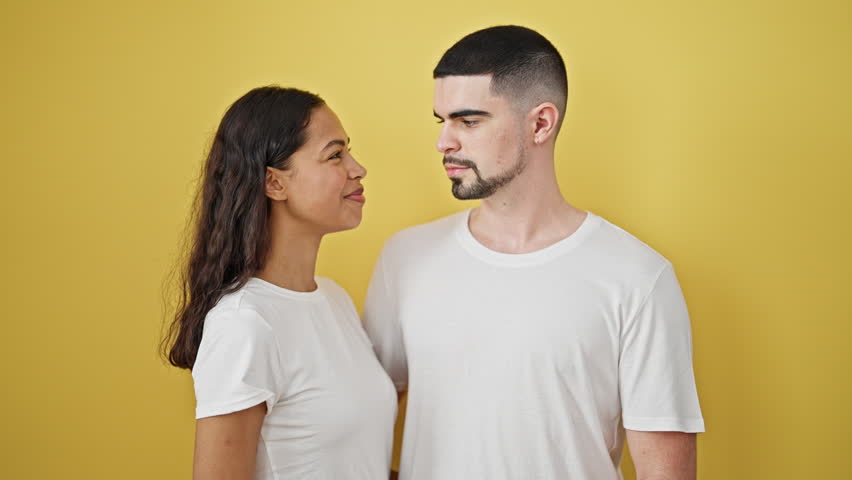 Confident beautiful couple smiling, making lovely heart gesture together, immersed in happiness and joy against a cool, isolated yellow background | Shutterstock HD Video #1111817627