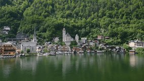 Aerial drone fly near Hallstatt town, Austria. Panoramic view of city shore and lake with Austrian mountains in background.