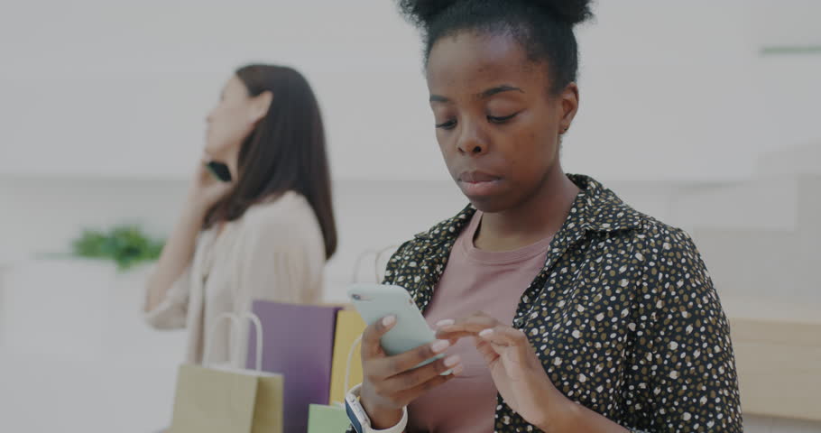 Cheerful woman using smartphone touching screen communicating in social media in shopping mall. Modern technology and lifestyle concept. | Shutterstock HD Video #1111822039