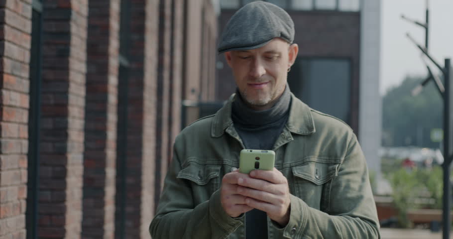 Dolly shot of pensive young man walking in city street using smartphone involved in online communication. Gadget and urban lifestyle concept. | Shutterstock HD Video #1111822071