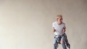 Laughing young man dancer in casual dancing in front of wall. People emotions lifestyle concept. Mock up copy space.
