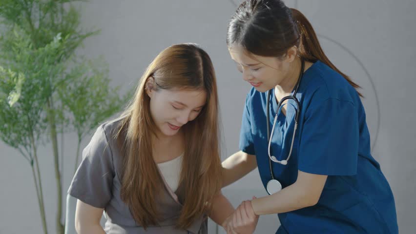 Asian doctor or nurse take care of pregnant woman to get up from sofa at clinic or hospital, gentle care, Doctor and Pregnancy Patient Concept, Doctor with stethoscope talking to patient  | Shutterstock HD Video #1111825021
