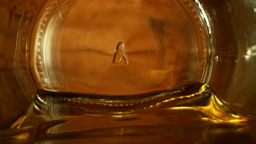 Super Slow Motion of Pouring Whiskey, Rum or Cognac Inside the Bottle. Lens is Moving Through the Bottle from Inside to Outside. Filmed on High Speed Cinema Camera, 1000fps.