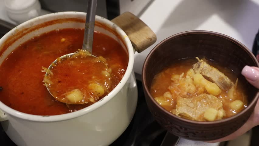 Borscht is poured into plates. Ukrainian traditional cuisine