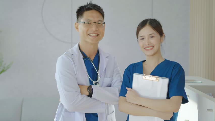 Two Friendly Doctors or nurse: Team Portrait of Male and female  Successful Medical Healthcare Professionals Standing in a Modern Hospital Office, Posing, Looking at Camera and Smiling.  | Shutterstock HD Video #1111828195
