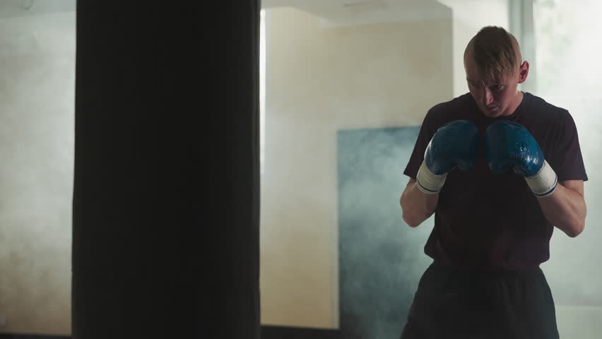 Athlete kicks hardly punching bag in sports center. Combat champion hits hanging equipment by leg in smoky gym slow motion. Body and mind training | Shutterstock HD Video #1111829407
