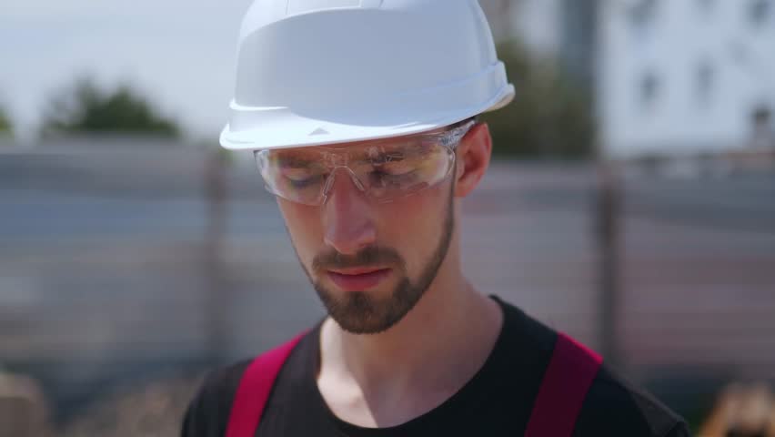Close up shot of Professional Construction Worker Wearing Hard Hat and Safety Glasses Holds Tablet Computer, Looking up and Down | Shutterstock HD Video #1111830253