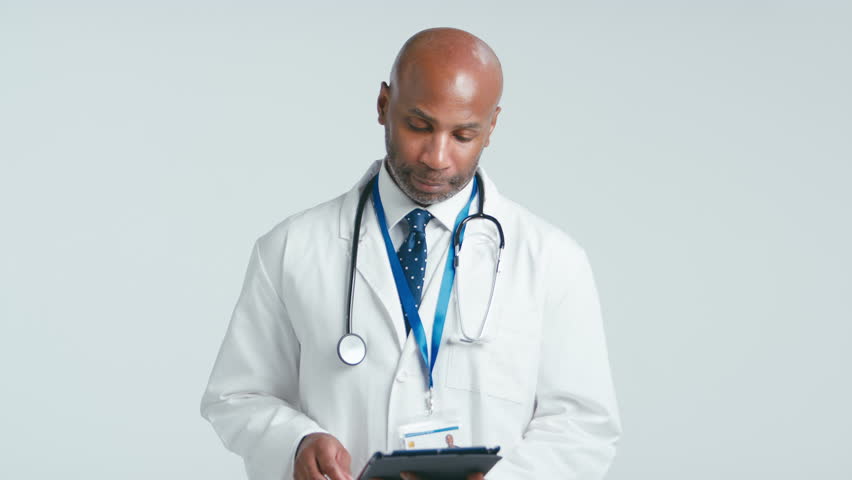 Studio portrait of mature male doctor wearing white coat holding digital tablet against white background - shot in slow motion | Shutterstock HD Video #1111830453