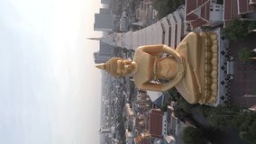 Vertical video. Stunning aerial view of the Giant Golden Buddha at sunset with a beautiful city skyline in the background. Bangkok, Thailand.