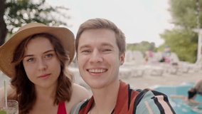 Happy caucasian couple have fun together and drinking cocktails at poolside. Young funny boyfriend with girlfriend recording video how the drink mojito on vacation. Self portrait of two lovers at - Powered by Shutterstock - Get 15% off with code: PIKWIZARD15