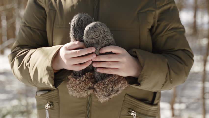 Caucasian european woman puts knitted mittens on her palms in cold winter. Close up of bare hands with mittens on frosty sunny morning. Protection from hypothermia and frostbite in winter season. Royalty-Free Stock Footage #1111836127