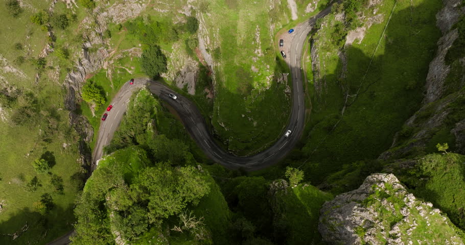 Top-down view of cars driving the epic roadway between evergreen Cheddar Gorge on sunny day. | Shutterstock HD Video #1111836383