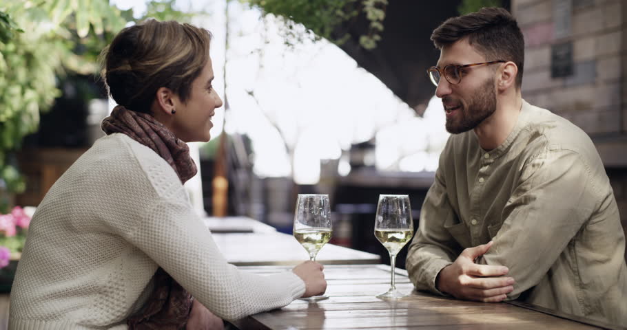 Wine, toast and a couple on a date at a restaurant with love, care and happiness together. A young man and woman cheers and drinking alcohol for anniversary, birthday or bonding at outdoor cafe | Shutterstock HD Video #1111840145