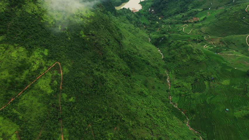 Drone of mountains, river and road for travel, eco tourism background or holiday adventure in Asian location. Aerial view of green landscape, clouds or fog on highway in Vietnam, Ma Pi Leng Pass