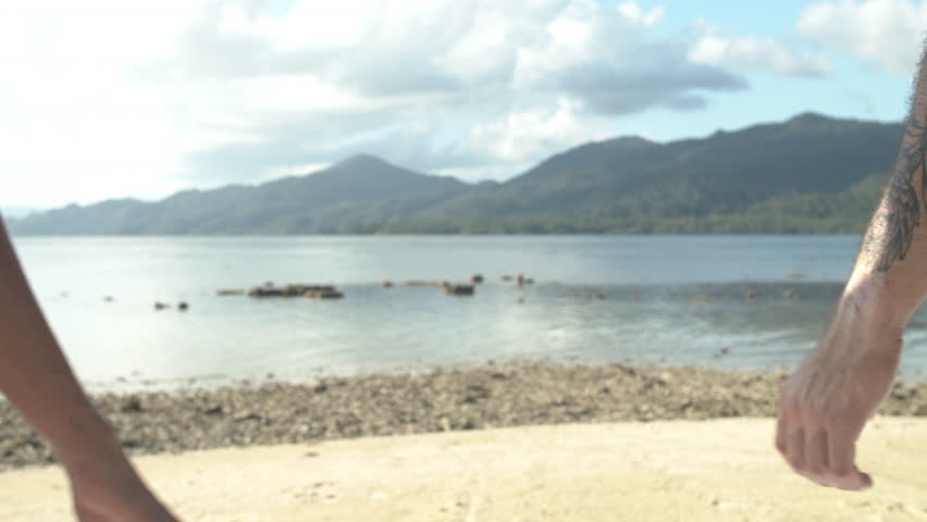 Couple, beach and holding hands for love, care or support together on outdoor vacation or holiday. Man and woman touching on ocean coast in summer for romantic getaway or bonding by natural sea water | Shutterstock HD Video #1111840379
