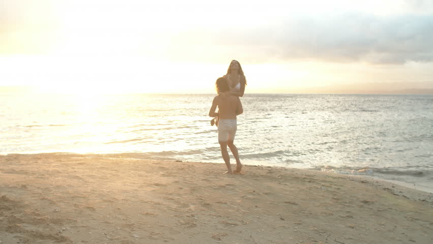 Happy couple, hug and beach in sunset for bonding, summer holiday or outdoor weekend vacation together. Man carrying woman in sky sunshine for love, embrace or support on ocean coast by sea water | Shutterstock HD Video #1111840381
