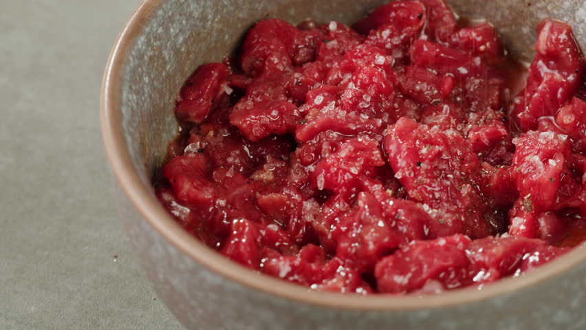 Chef sault Raw beef meat tartar with sauce, man cooking steak tartare, making delicious french dish in modern restaurant. Fresh eco angus meat.  | Shutterstock HD Video #1111842469
