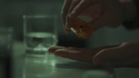 In front of a kitchen table, a depressed Caucasian man carefully selects pills. The index finger moves the pills, finds the right drug to combat daily stress - Powered by Shutterstock - Get 15% off with code: PIKWIZARD15