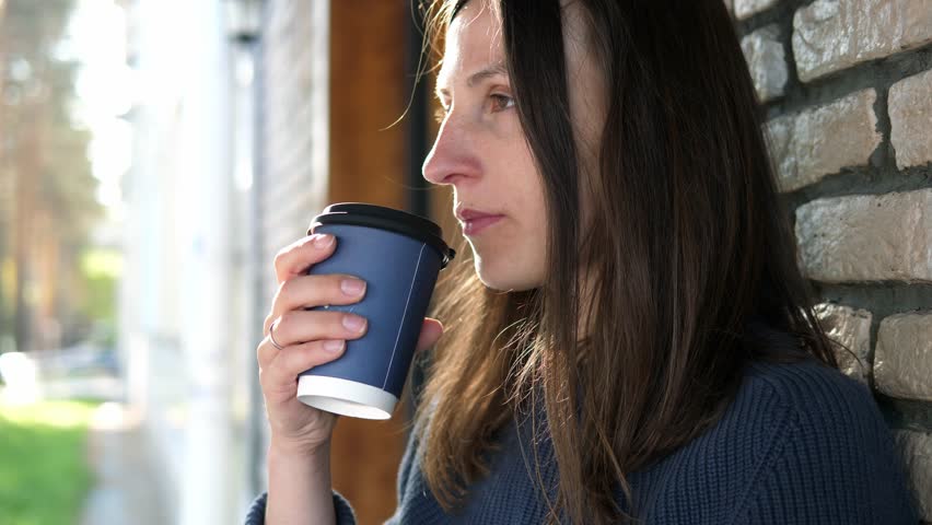 Young woman drinks a delicious hot invigorating drink coffee and enjoys life | Shutterstock HD Video #1111850075